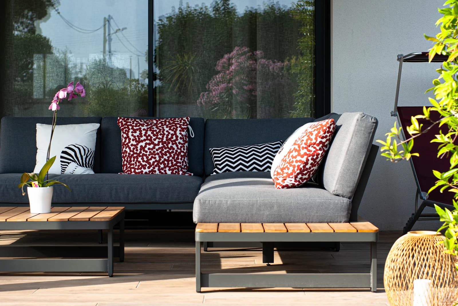 Assises et coussins sur une terrasse devant une baie vitrée.