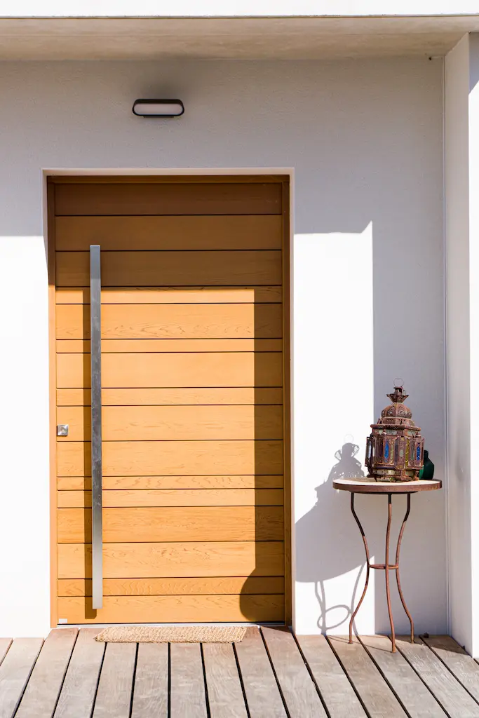Entrée d’une maison contemporaine à Albi avec porte en bois et façade claire.