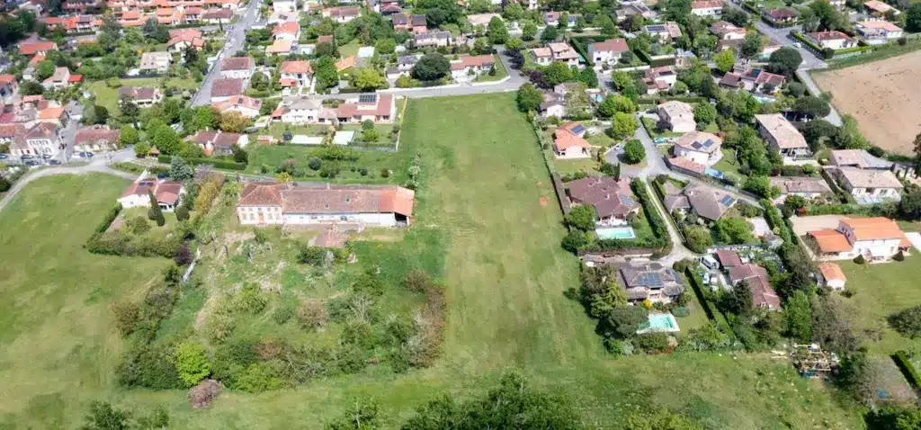 Projet de construction maison sur-mesure à Labège – CELIA Création Vue aérienne d’un futur projet de construction CELIA Création à Labège, montrant un grand terrain constructible entouré de maisons individuelles dans un quartier résidentiel.