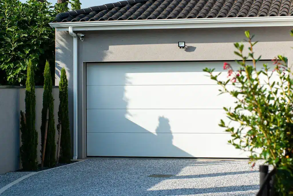 Garage d’une maison contemporaine sur-mesure réalisée par CELIA Création à Castelmaurou, maison familiale avec toit tuiles et aménagement extérieur.