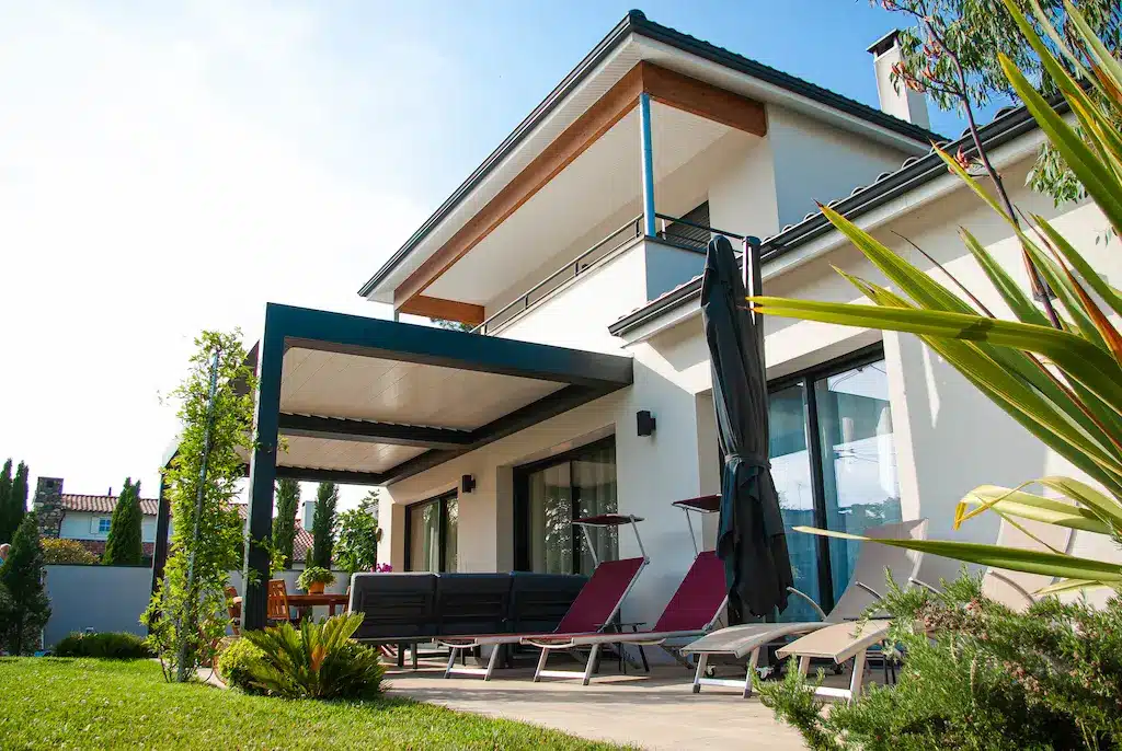 Terrasse couverte d’une maison contemporaine à étage réalisée par CELIA Création à Castelmaurou, maison familiale sur-mesure avec espace détente extérieur et jardin.