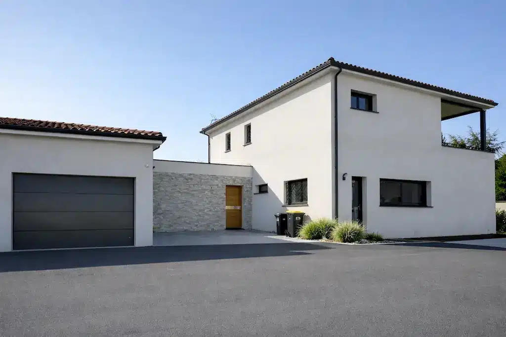 Entrée et garage d’une maison contemporaine à étage réalisée par CELIA Création à Gragnague avec façade claire, toiture en tuiles et architecture moderne.