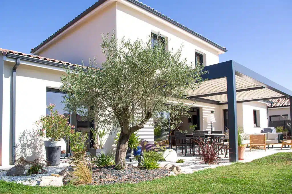 Maison contemporaine à étage avec pergola bioclimatique et jardin paysager réalisée par CELIA Création à Gragnague.