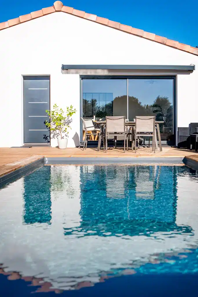 Terrasse avec piscine devant une maison moderne de plain-pied réalisée par CELIA Création à Tournefeuille en Haute-Garonne